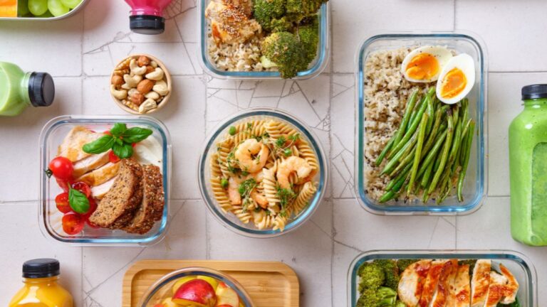 Alt text for cover image: Glass containers with rice, pasta, chicken, and veggies for budget meal prep.
