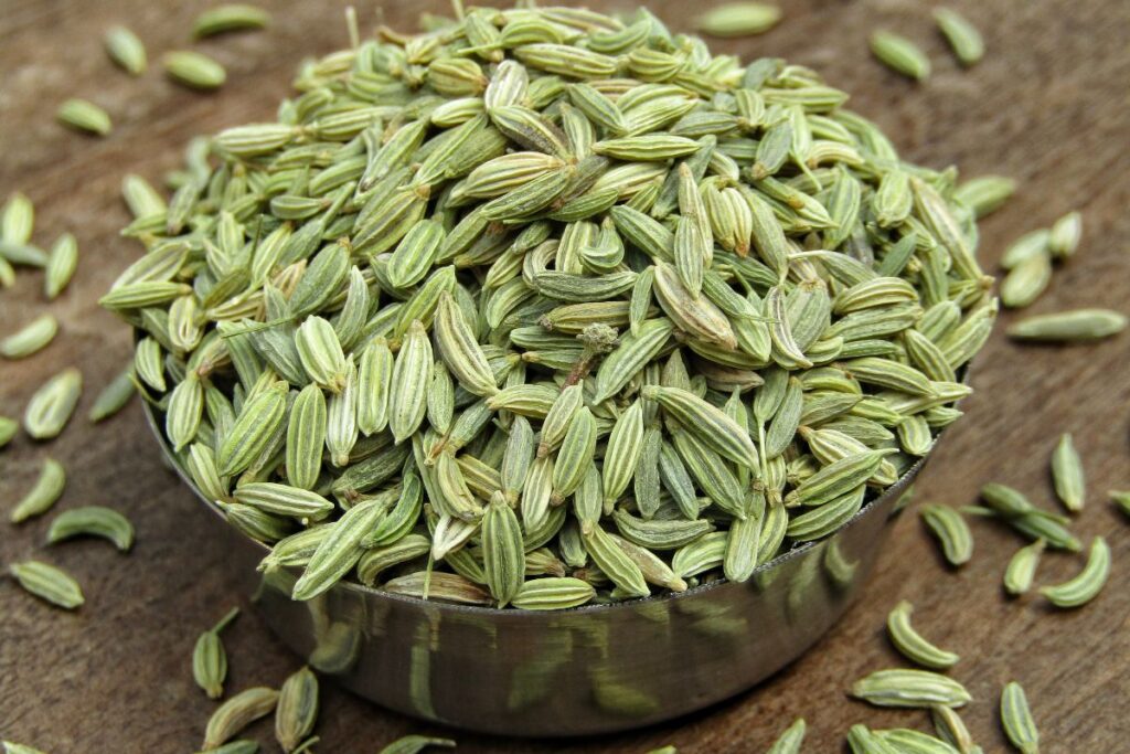 Close up of fennel seeds on a wooden board.