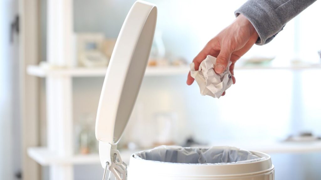 Sprinkling baking soda in trash can to reduce garbage odor.