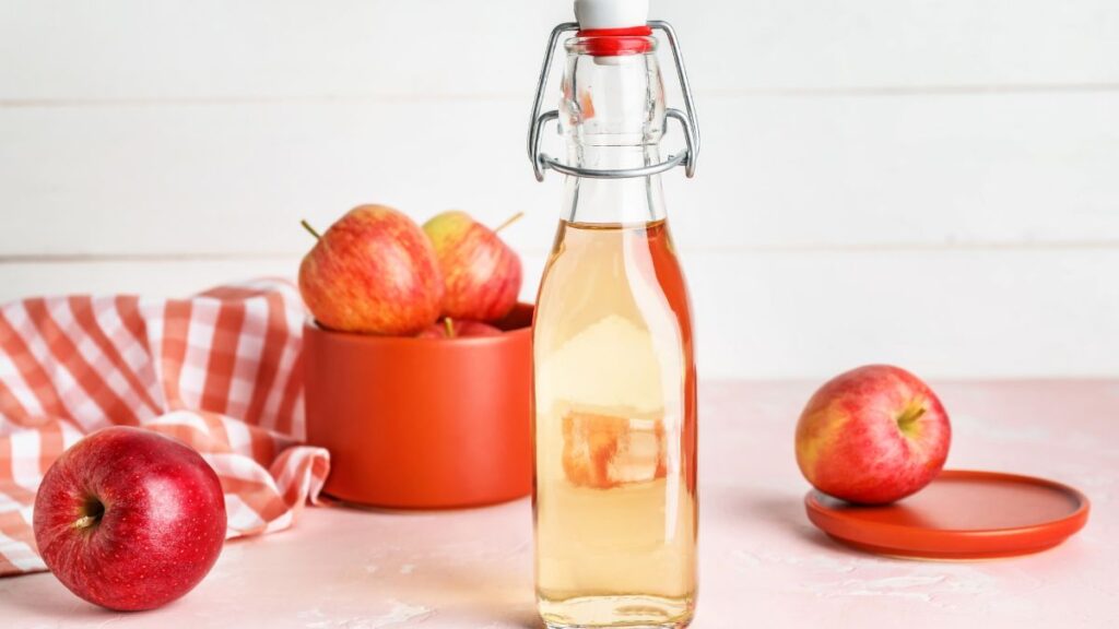 Small glass bottle of apple cider vinegar for fruit fly trap.