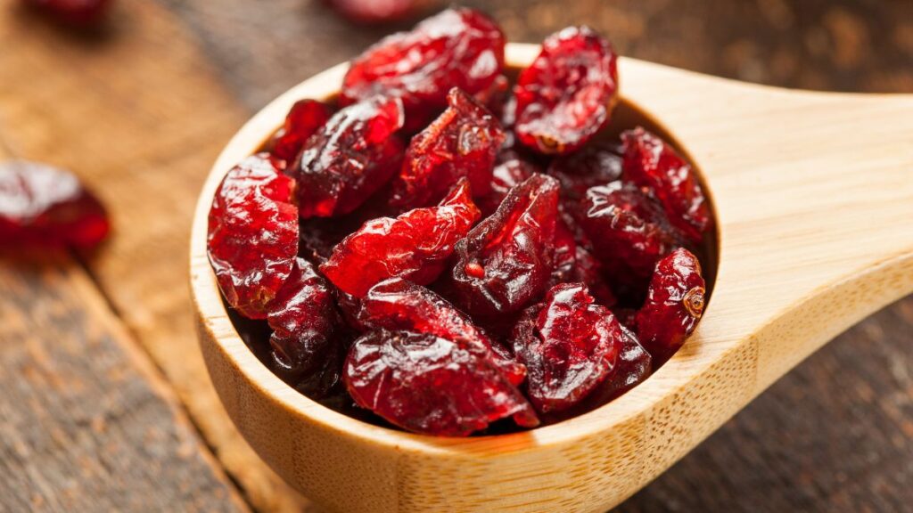 Dried cranberries on a wooden spoon.