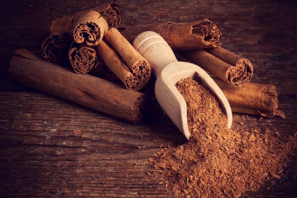 Ground and whole cinnamon on a wooden board.