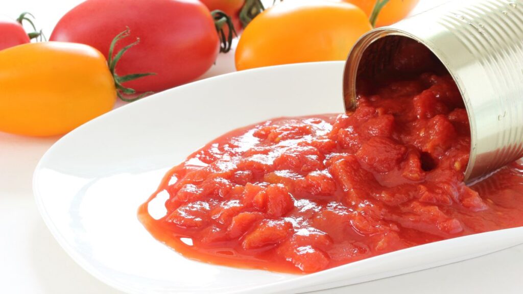 Canned tomatoes being poured on a plate.