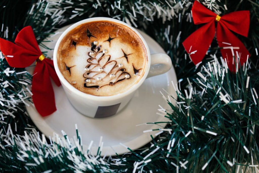 Festive holiday coffee with Christmas tree foam art, surrounded by garland and bows.