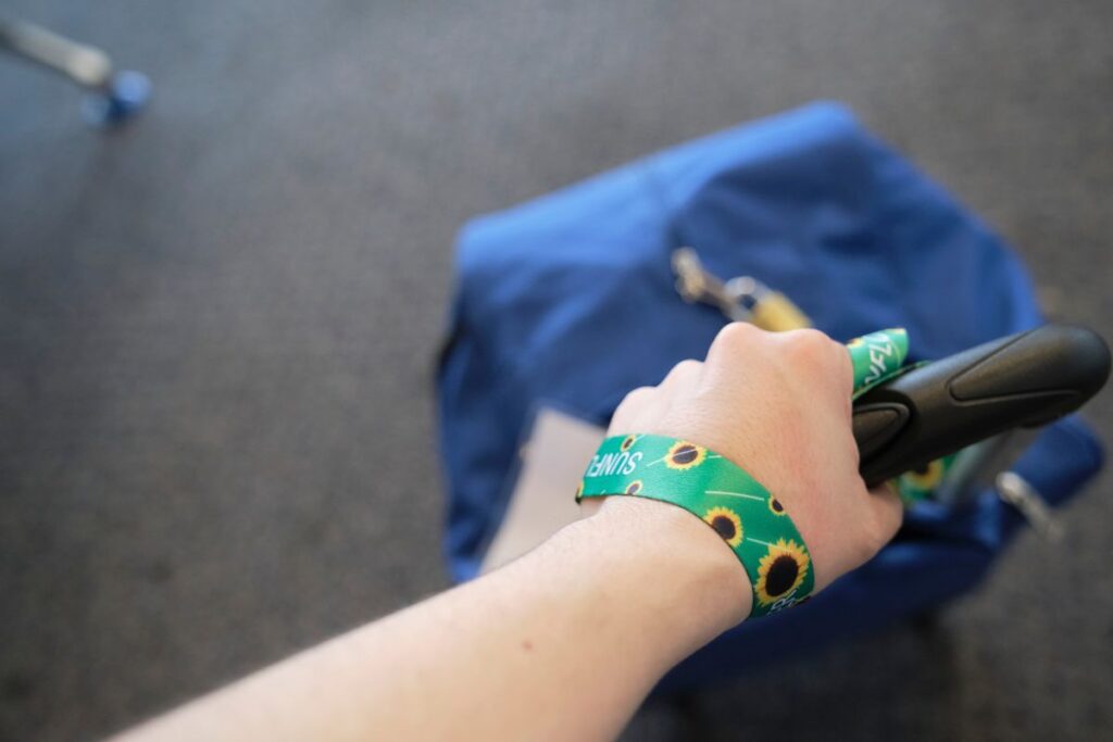 Traveler holding luggage handle with a Hidden Disabilities Sunflower wristband.