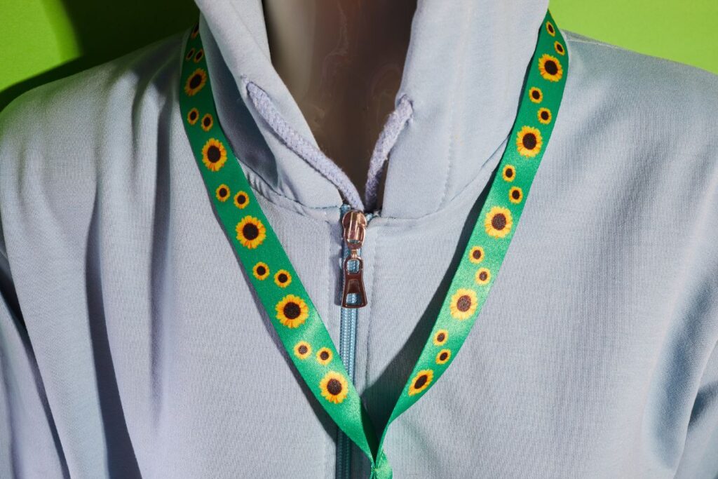 Close-up of a Hidden Disabilities Sunflower lanyard worn over a hoodie.
