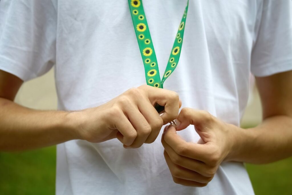 Hands adjusting a Hidden Disabilities Sunflower lanyard on a plain shirt.