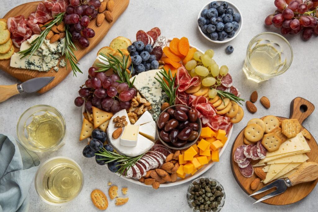 Charcuterie board with meats, cheeses, grapes, nuts, and holiday appetizers.