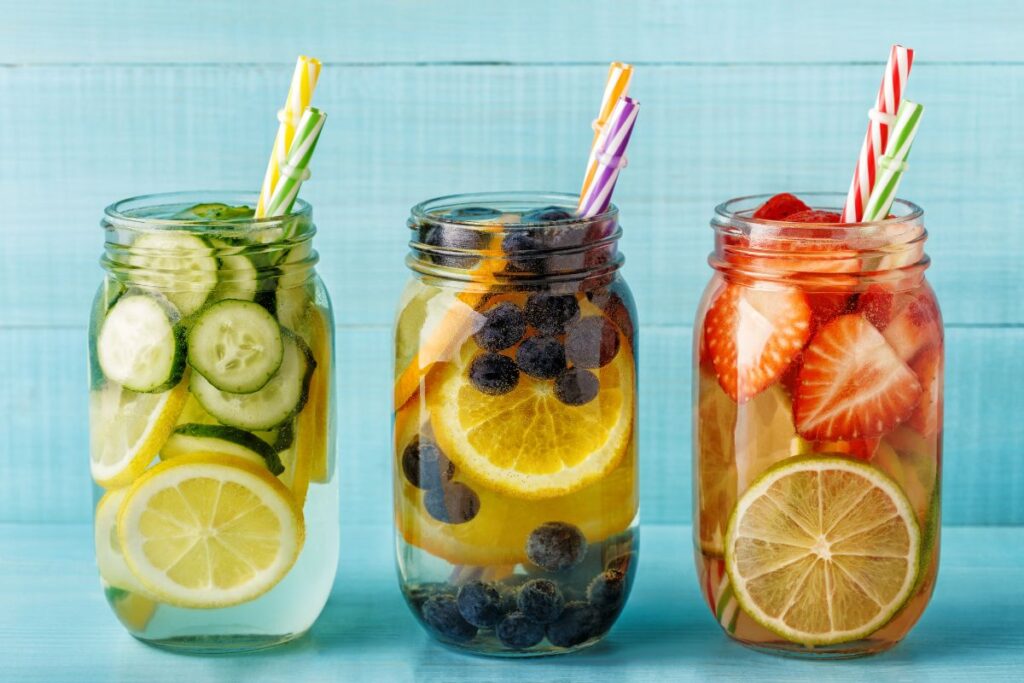 Mason jars filled with fruit-infused water made with lemon, berries, and cucumber.