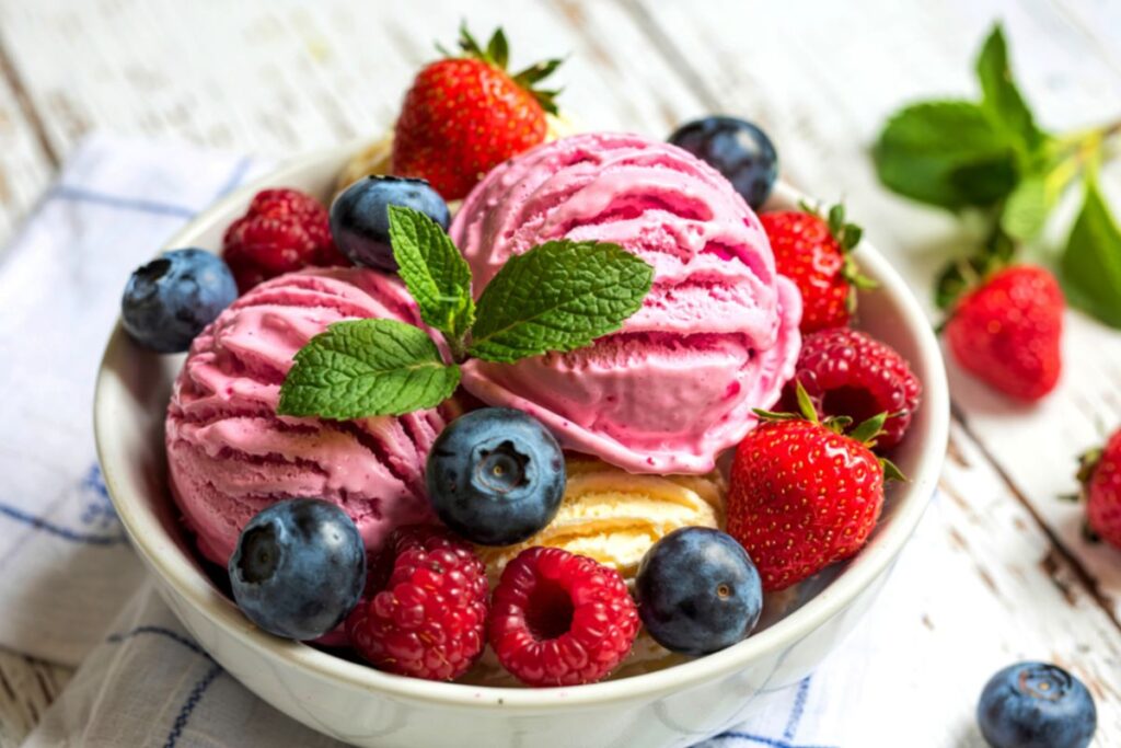 Ice cream bowl topped with fresh strawberries, raspberries, and blueberries.