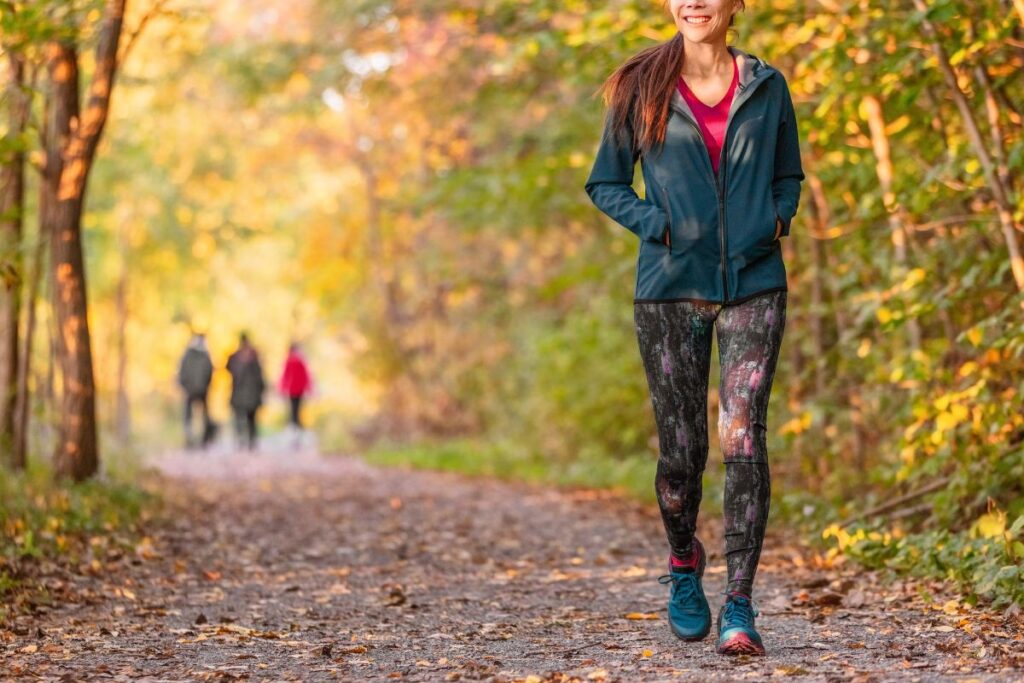Smiling woman walking outdoors in nature, showing exercise as a natural way to boost dopamine.