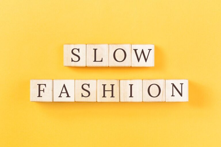 Slow fashion concept spelled out with wooden blocks on yellow background.