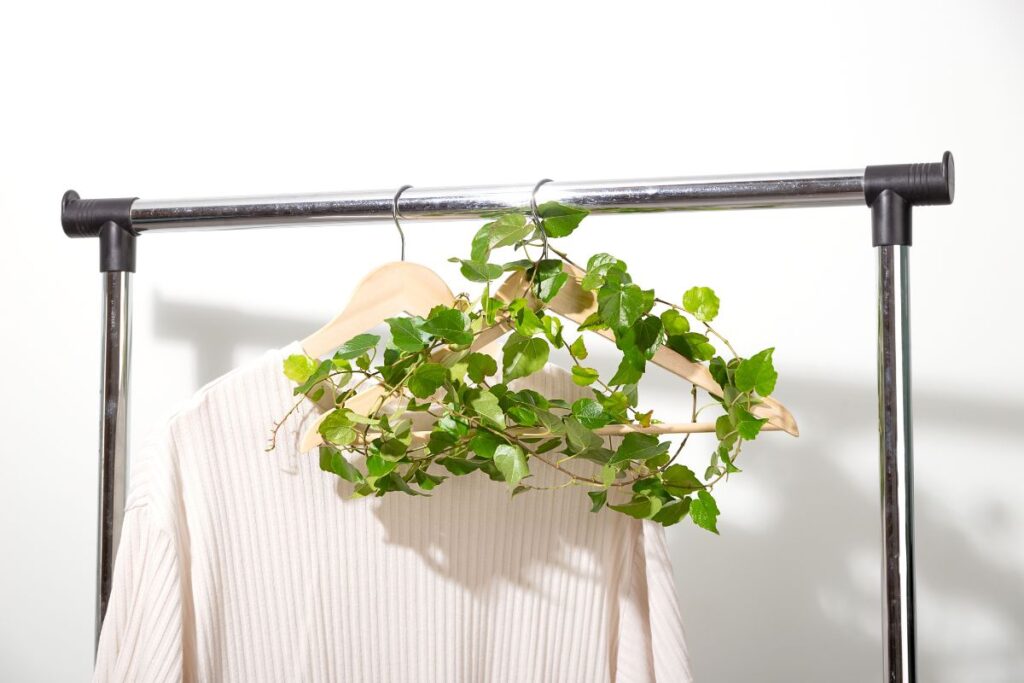 Minimal white shirt on hanger decorated with green leaves for sustainable living.
