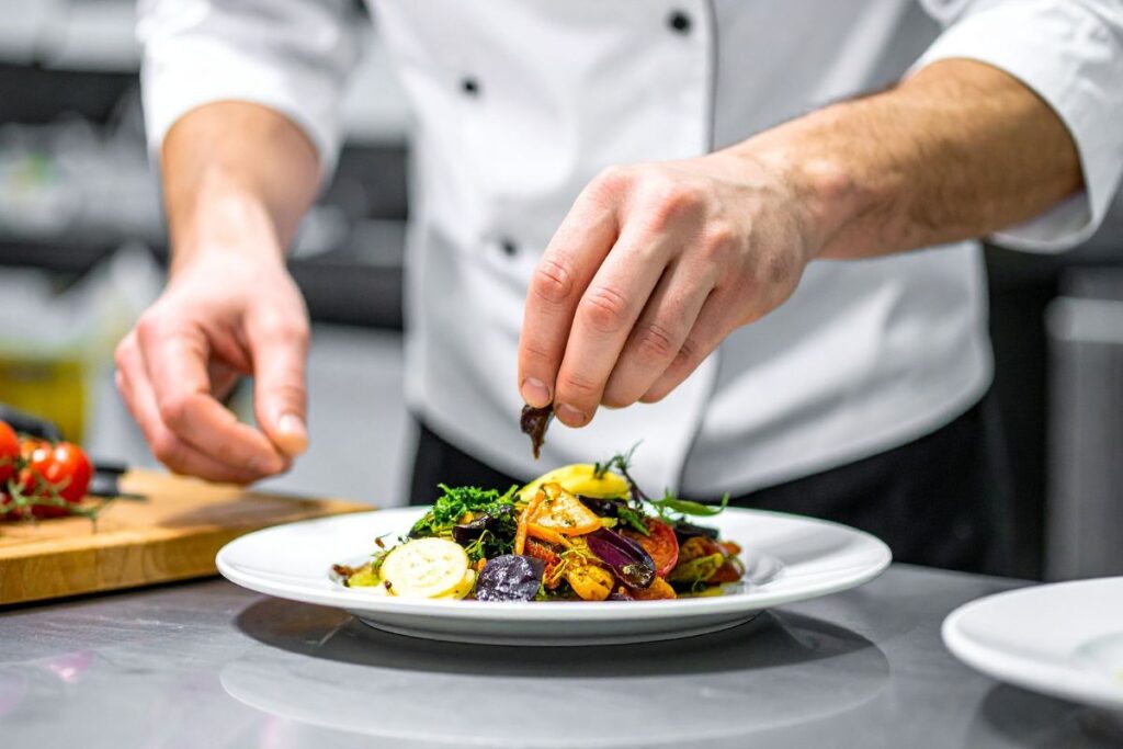 Chef in a modern kitchen plating a colorful gourmet vegetable dish.