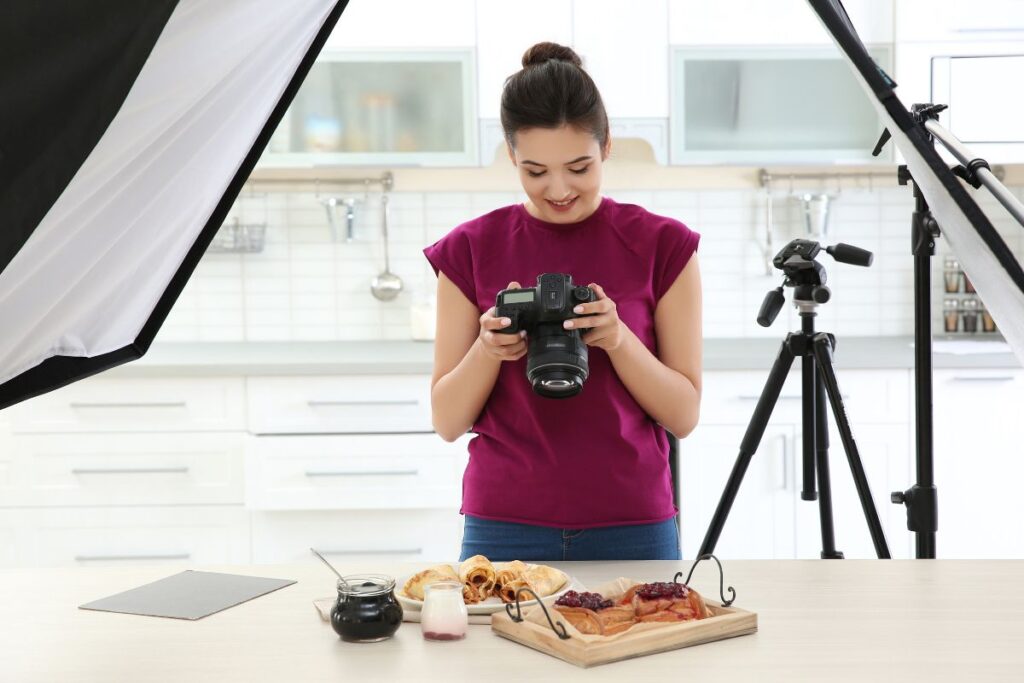 Food photographer capturing plated dishes in a bright home kitchen studio.