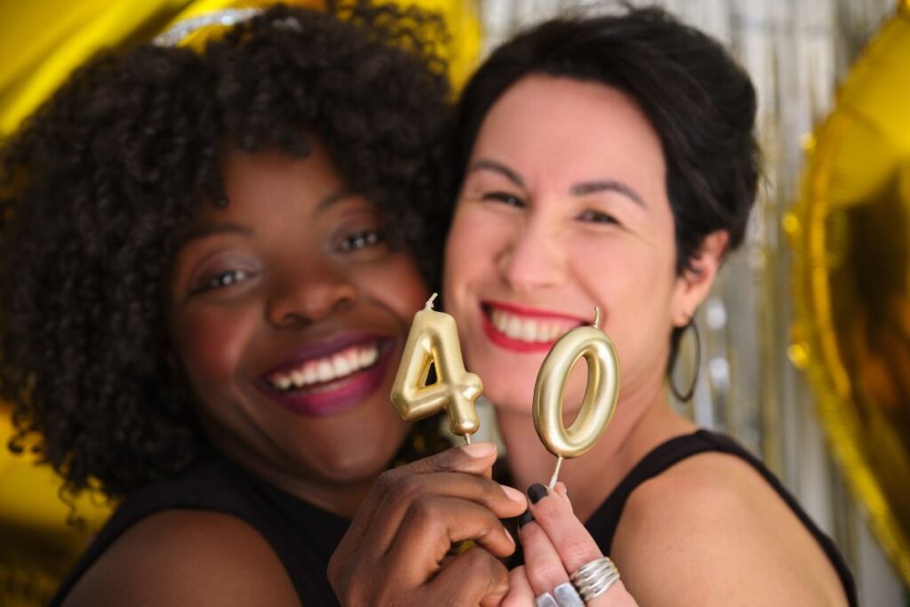 Joyful friends celebrating a 40th birthday with gold candles and big smiles.