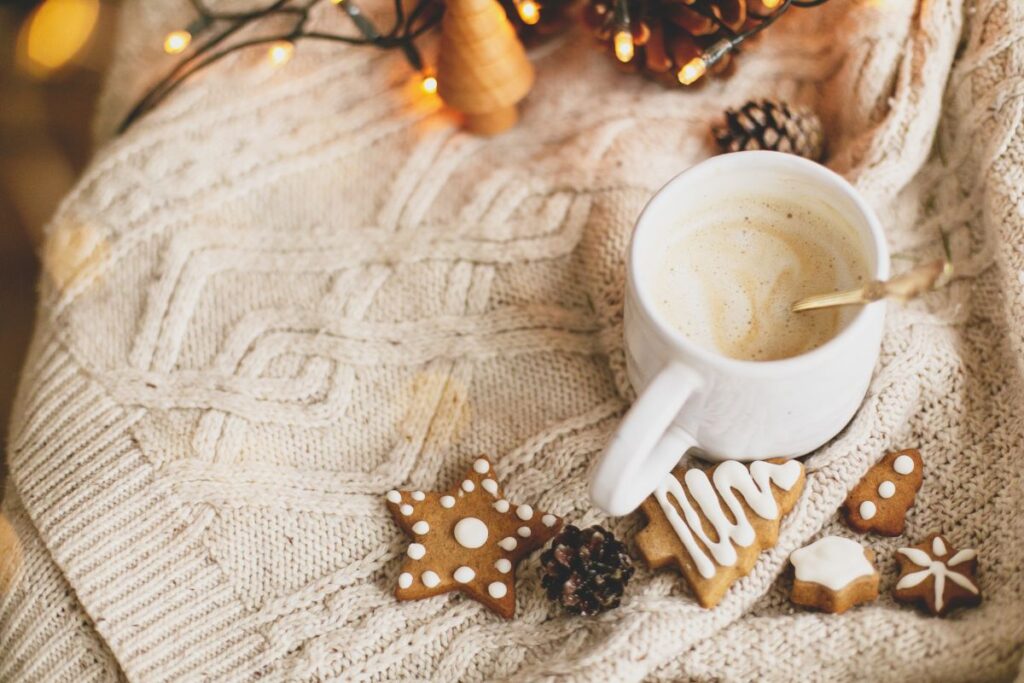 Festive coffee with holiday cookies, twinkle lights, and cozy blanket.