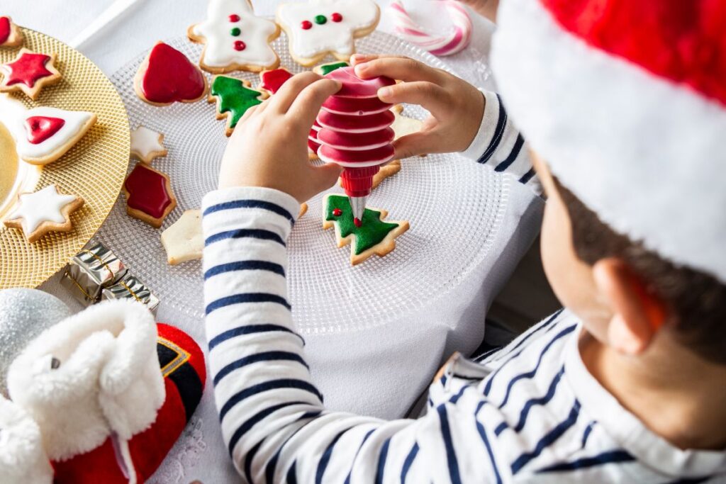 Child decorating Christmas cookies with icing during holiday traditions.
