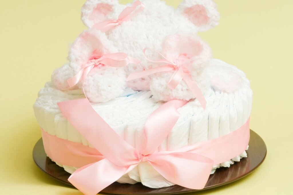Diaper cake decorated with a pink ribbon and topped with soft plush baby booties.