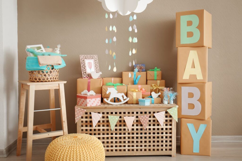 Baby shower setup with pastel gifts, BABY block décor, and hanging cloud decor.