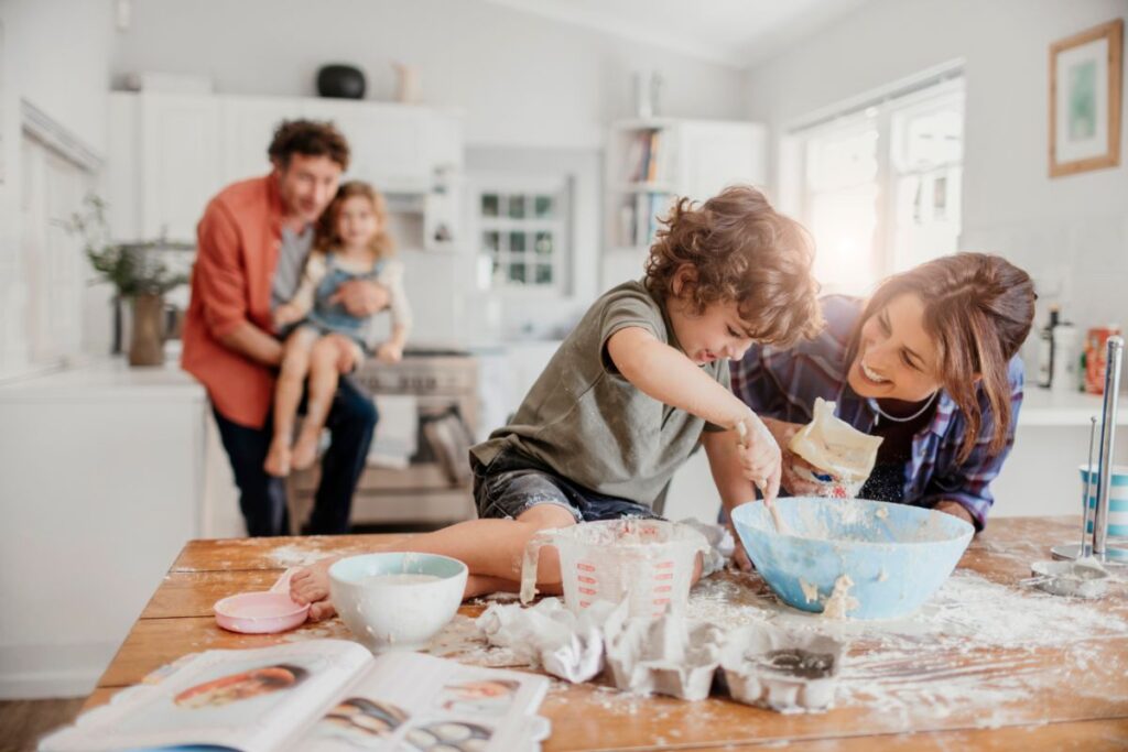 Family baking together in the kitchen with young child mixing ingredients.