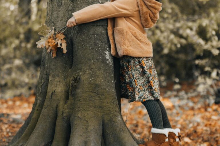 Child in warm autumn clothing hugging a large tree, symbolizing comfort, warmth, and belonging.