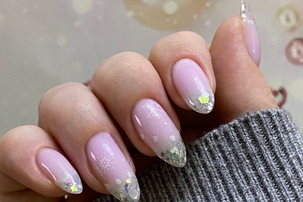 Light pink snowflake nails with subtle glitter tips and sparkle.