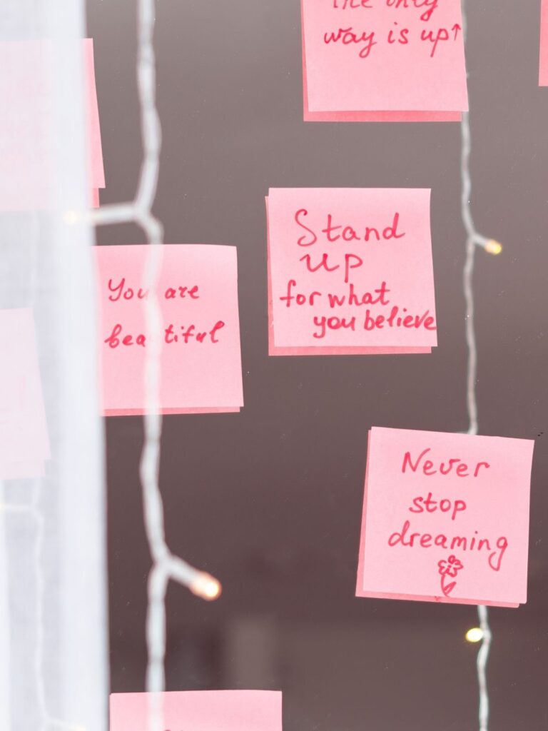 Affirmations written on sticky notes and put on a wall.