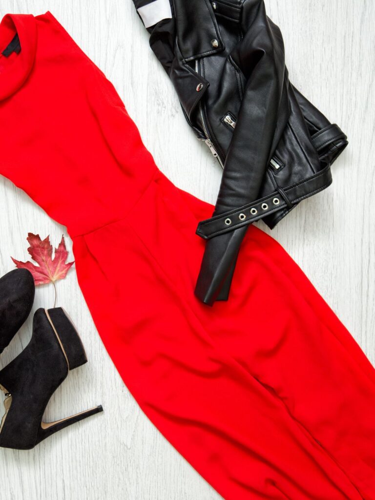 Flatlay of a red dress with a black leather jacket and high-heeled boots, styled for an elegant date night outfit for women over 50.