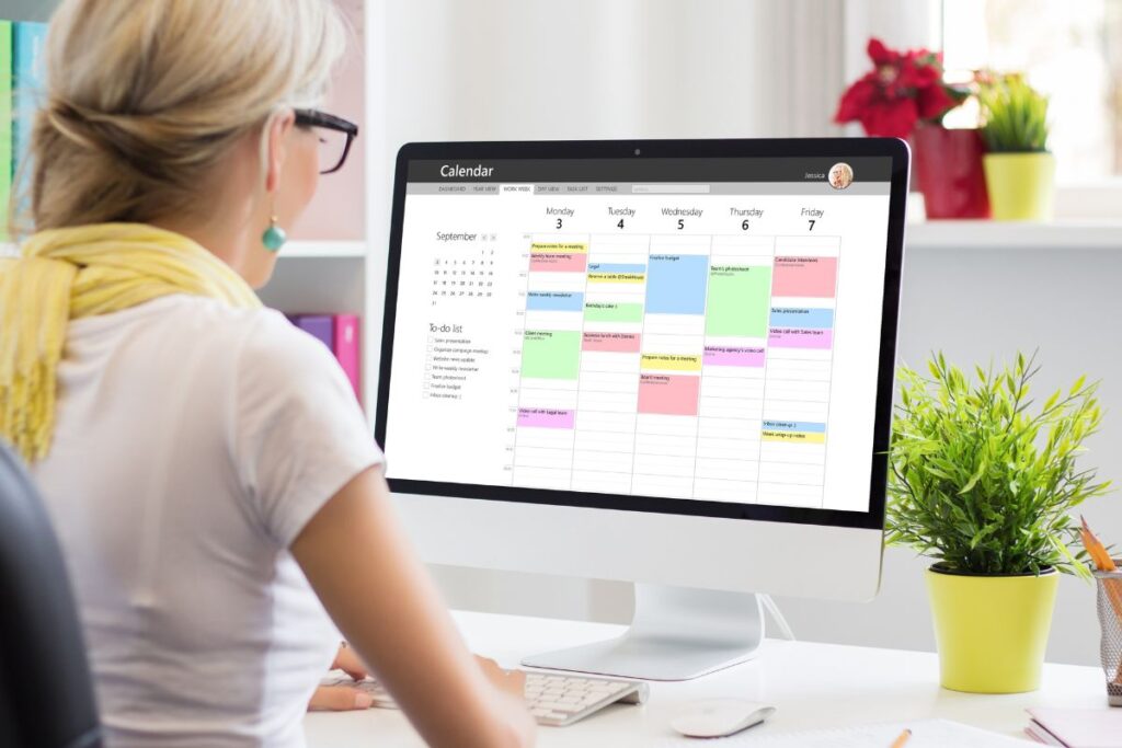 Woman using digital planner on computer screen.