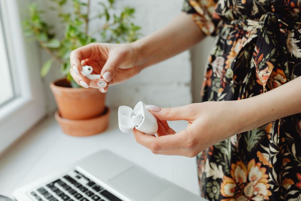Woman holding wireless earphones on a work desk.