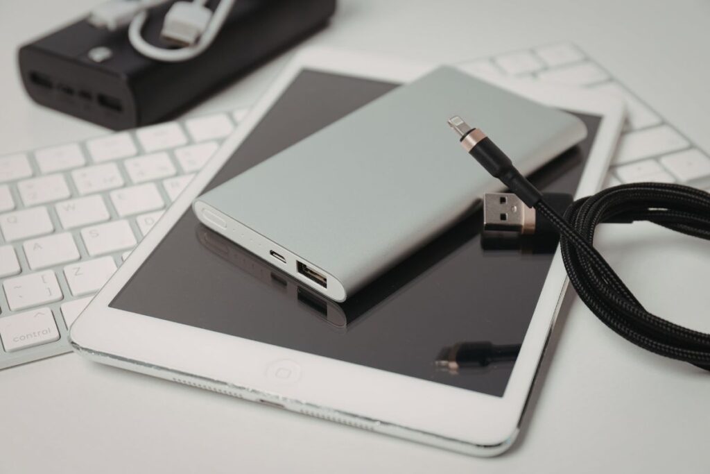 A tablet and laptop placed near a portable power bank.