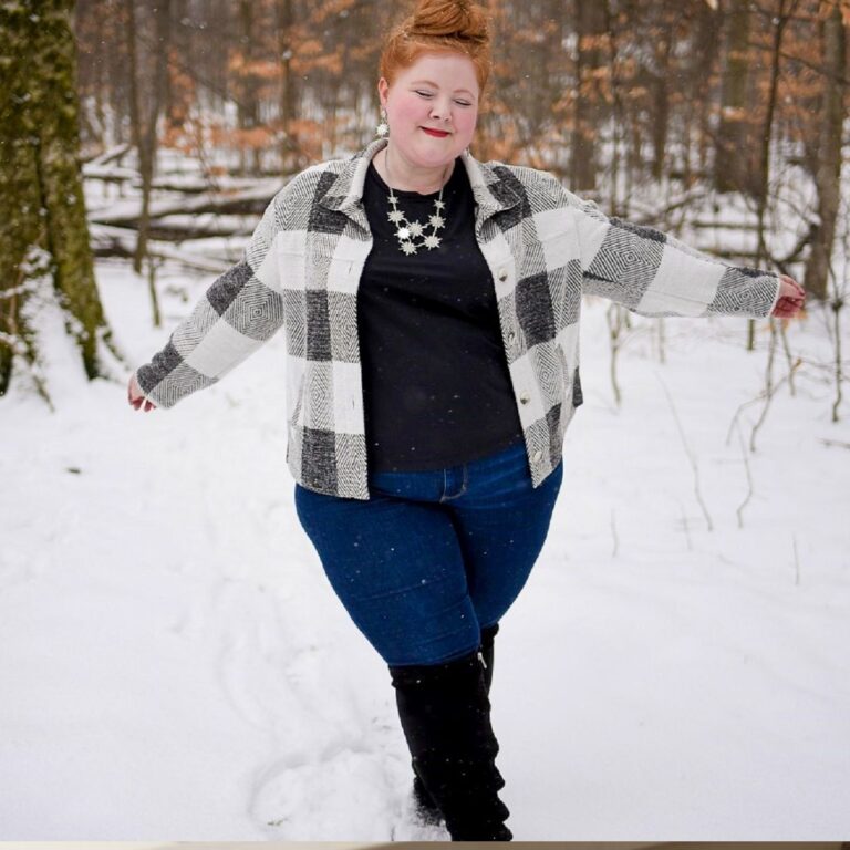 Woman in plaid jacket and jeans standing in the snow