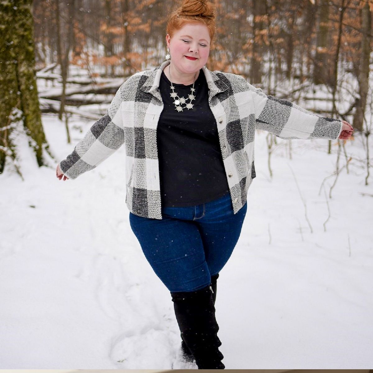 Woman in plaid jacket and jeans standing in the snow