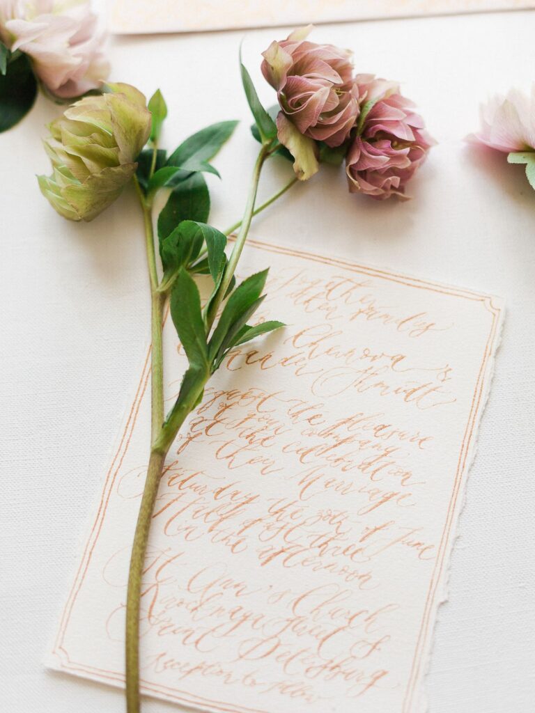 Handwritten letter on textured paper with soft flowers resting beside it.