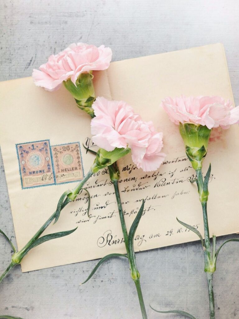 Vintage envelope with handwritten letter, postage stamps, and soft pink flowers
