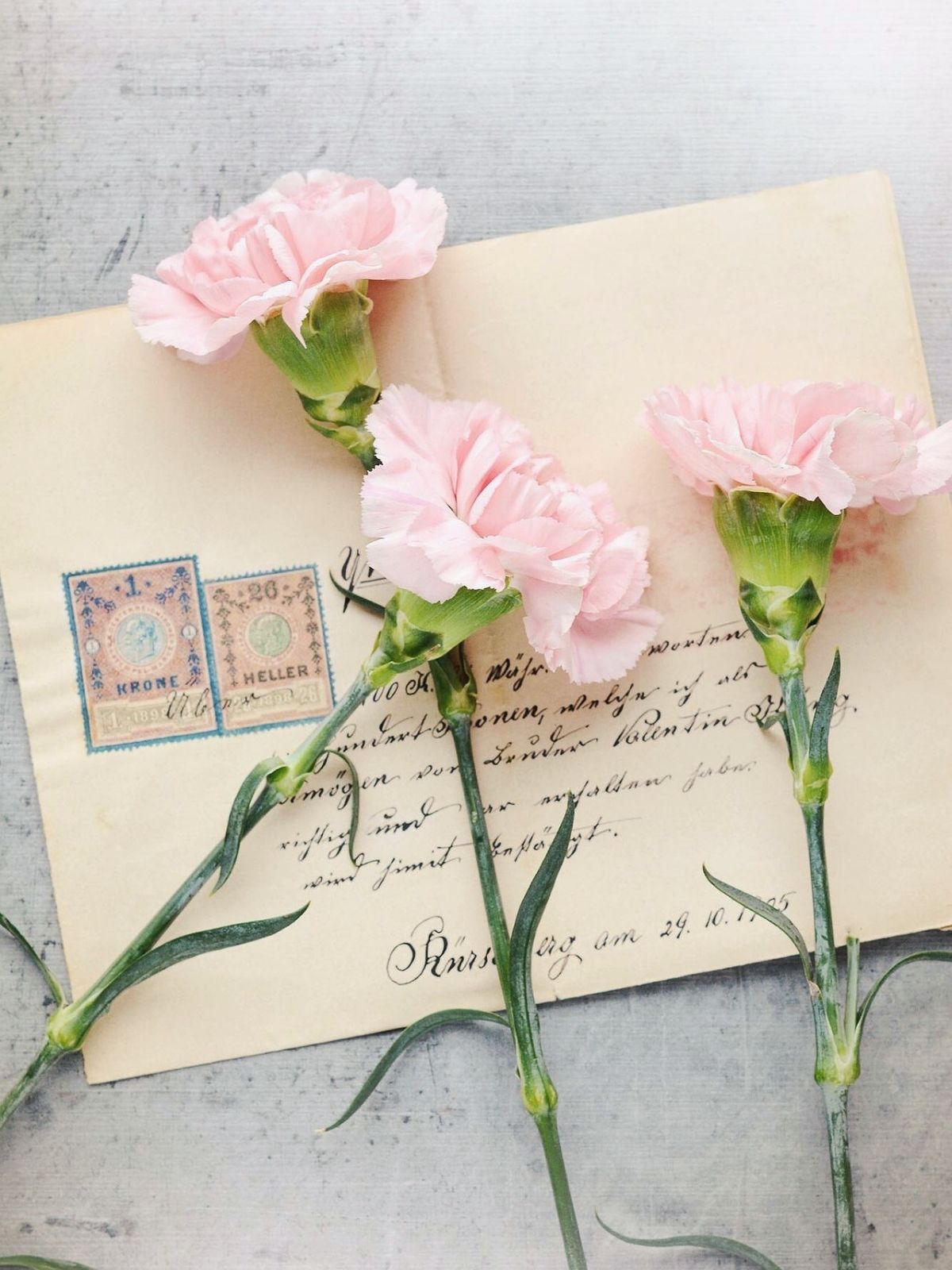 Vintage envelope with handwritten letter, postage stamps, and soft pink flowers