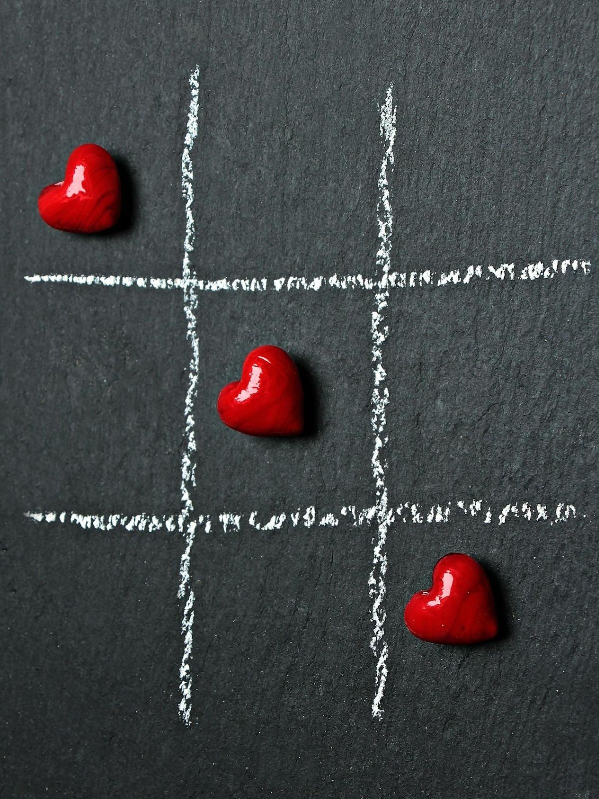Heart-shaped game pieces on a chalkboard grid for Valentine’s Day games.