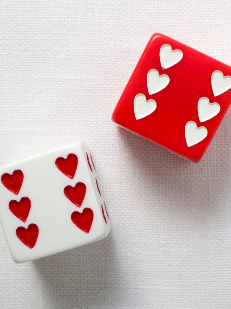 Valentine’s Day dice with red and white hearts on a neutral background.