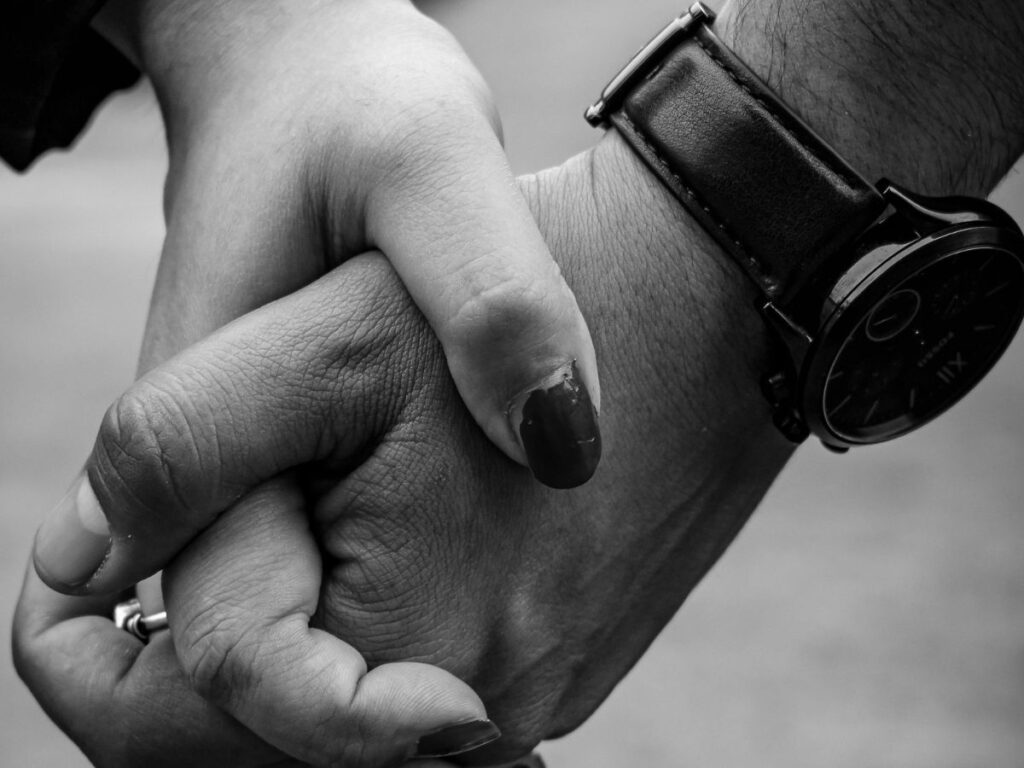 Close-up of a couple holding hands, one wearing a wristwatch.