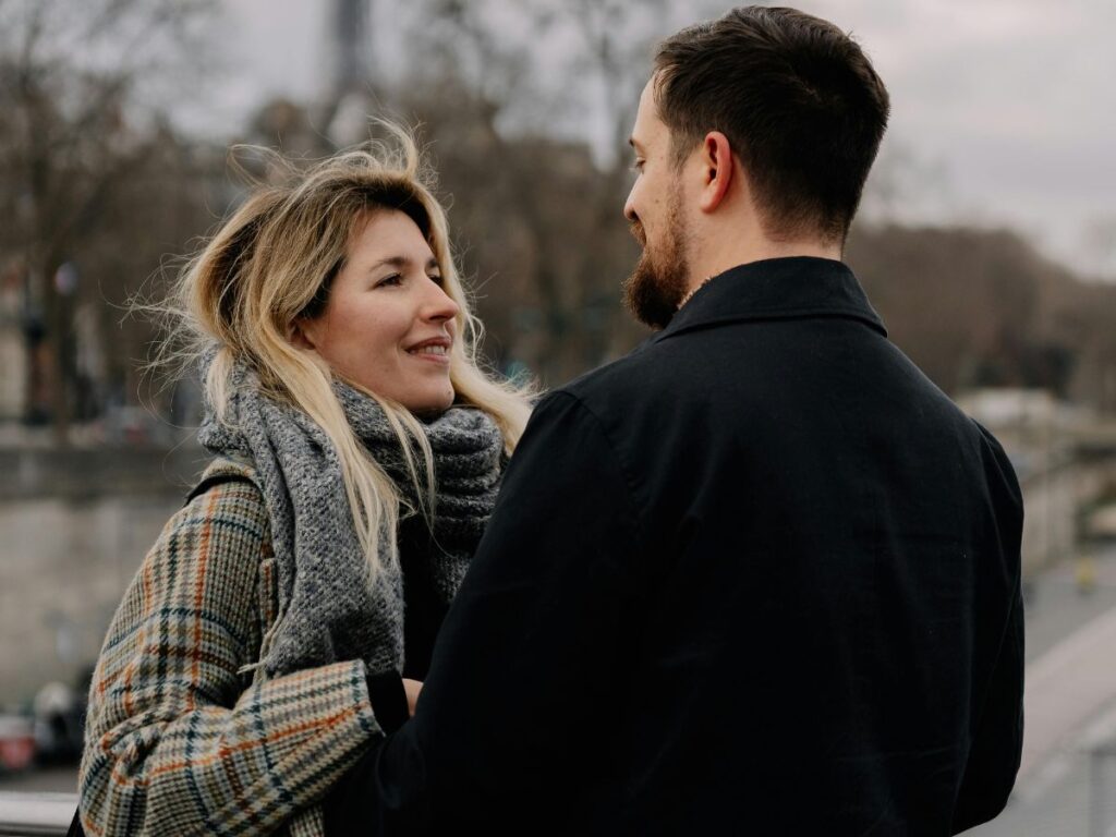 Couple embracing near the Eiffel Tower on an overcast day.