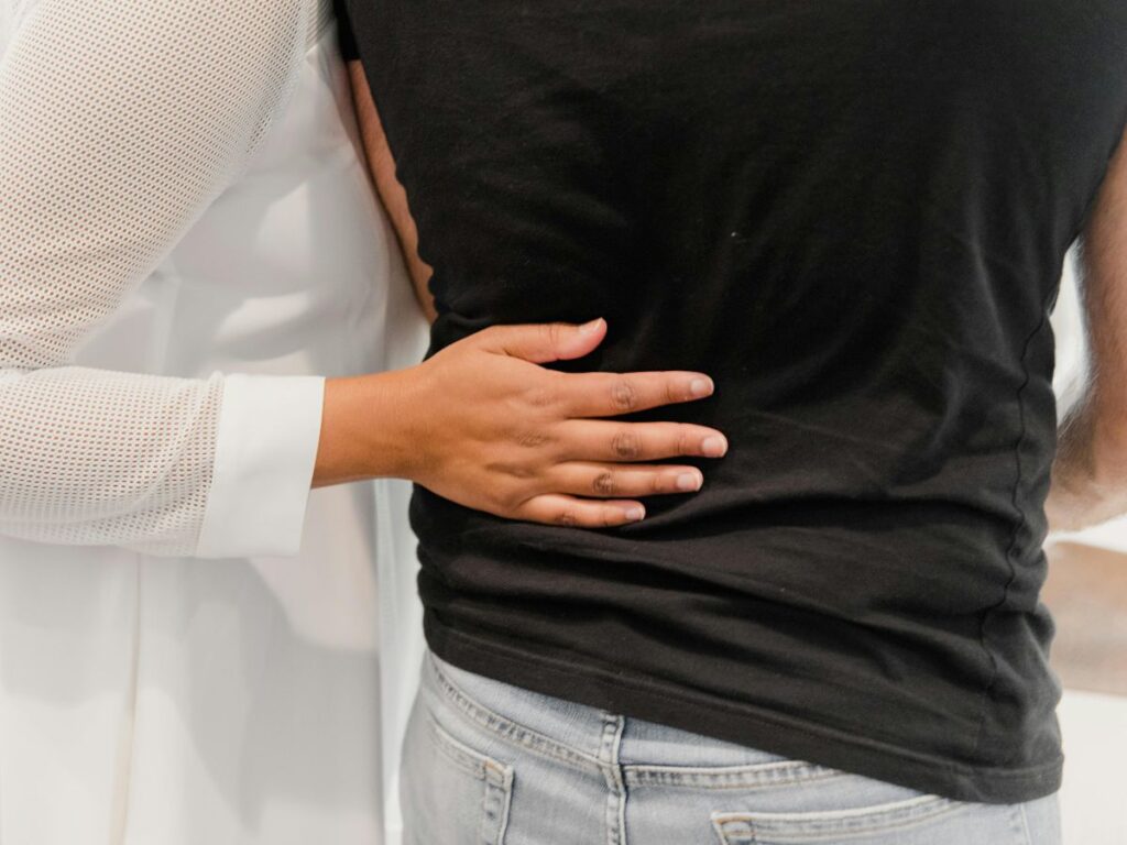 Close-up of a woman’s hand resting gently on a man’s back in an embrace.
