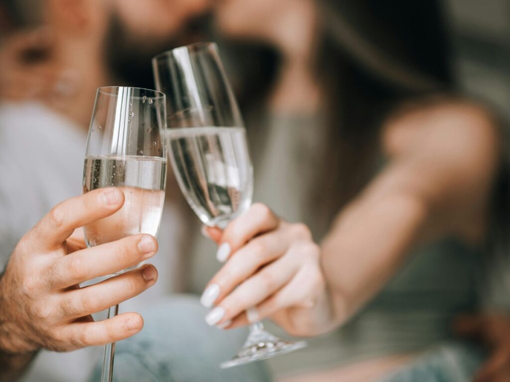 Two people clinking champagne glasses in a celebratory toast.