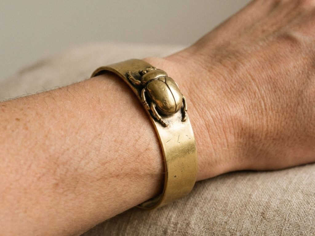 Wrist wearing gold beetle cuff bracelet close-up