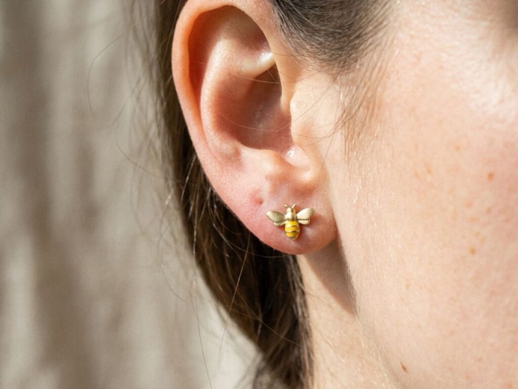 Bee-shaped stud earring on ear close-up