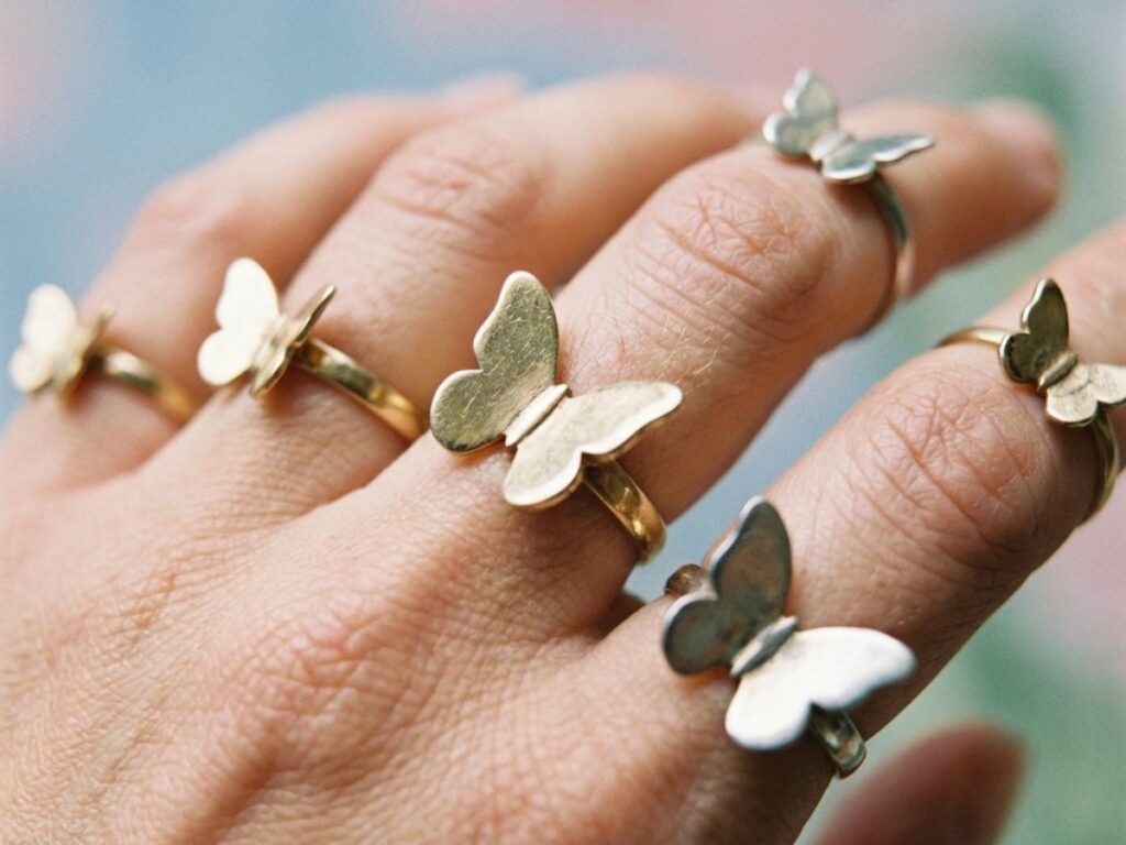 Hand wearing multiple butterfly rings close-up