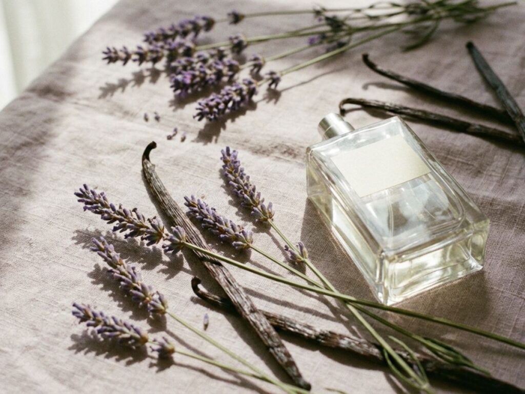 Perfume bottle with lavender flowers and vanilla pods on neutral fabric