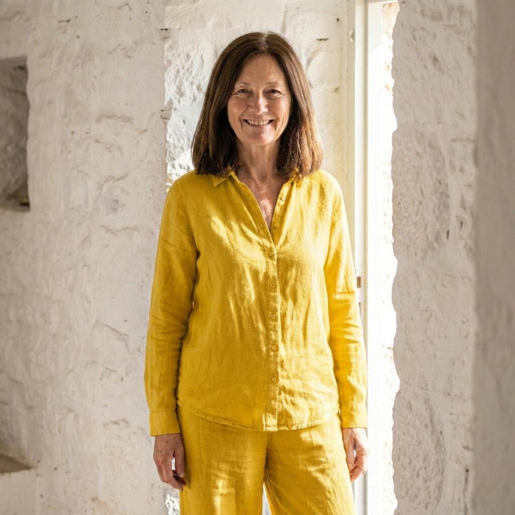 A woman smiles indoors wearing a bright yellow matching linen set, creating a bold and cheerful warm-weather outfit.