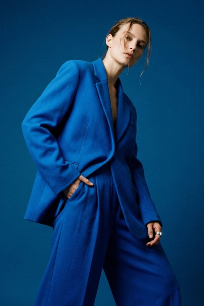Woman in bright blue oversized suit posing against blue background.