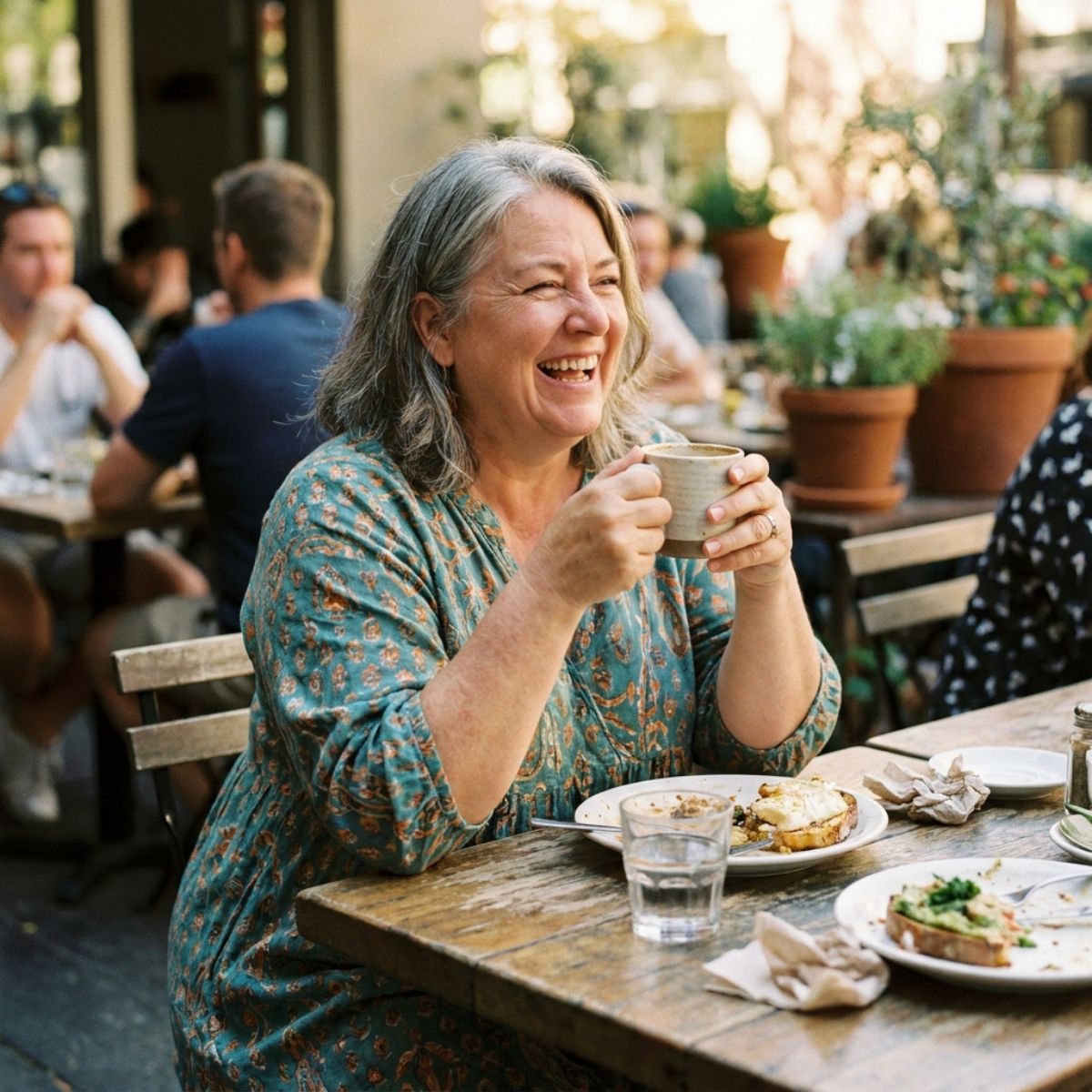 Smiling woman enjoying coffee and breakfast at outdoor café